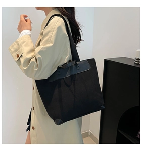 Detail of black corduroy tote bag with leather accents and wide shoulder strap