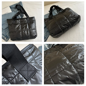 Macro detail of black quilted tote bag showing padded fabric and durable strap stitching