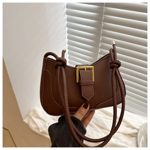 Détail du sac sous l'aisselle marron avec boucle dorée et bandoulière à nœuds chic