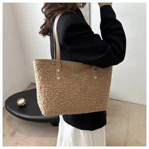 Detail of camel plush tote bag with leather handles and gold rivet accents for fall winter
