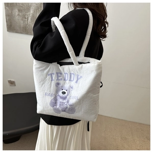 Detail of the stuffed cotton shoulder strap on a white canvas tote with teddy bear print