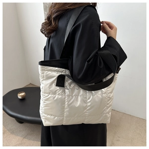 Détail de la texture du sac cabas matelassé blanc et de la large bandoulière noire
