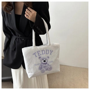 Detail of white quilted puffer tote bag with purple teddy bear print and soft handles
