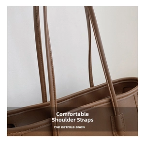 Detail shot of sturdy double shoulder straps and fine stitching on a brown tote bag