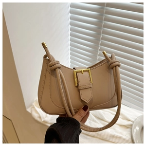 Détail du sac croissant beige avec boucle en métal doré et bandoulière à nœuds
