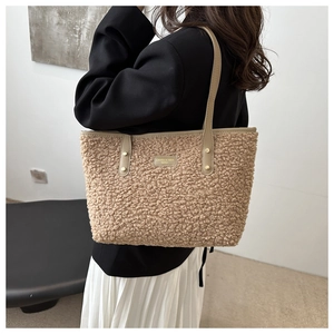 Close-up of camel teddy fleece tote bag with leather logo patch and thin shoulder strap