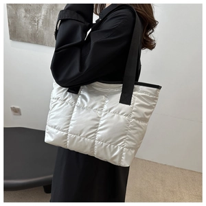 Sac cabas matelassé argenté avec finition métallique et bandoulières noires sur modèle