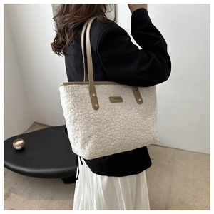 Detail of white faux shearling tote bag with khaki leather trim and shoulder strap