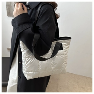 Détail d'un grand sac cabas blanc matelassé avec des anses noires contrastées sur un modèle