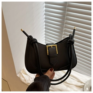 Détail du sac hobo en cuir noir mat avec boucle dorée décorative et bandoulière nouée