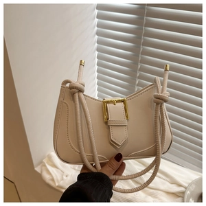 Détail d'un sac demi-lune blanc cassé avec boucle dorée et bandoulière en corde torsadée