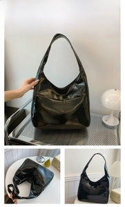 Detail view of glossy black leather hobo bag with wide shoulder strap and front pocket