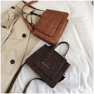 Gros plan de sacs à bandoulière vintage en cuir marron avec lettrage doré