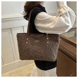 Close-up of brown lamb wool tote bag featuring leather straps and metal brand plate