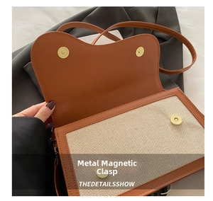 Close-up of magnetic buckle on vintage brown leather and canvas crossbody bag