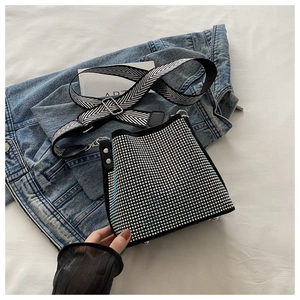 Detail view of rhinestone bucket bag with woven strap on denim jacket background