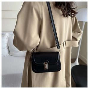 Detailansicht einer schwarzen Retro-Umhängetasche mit goldenem Drehverschluss am Model