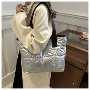 Détail du sac cabas matelassé argenté avec sa bandoulière noire en nylon brillant