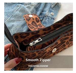 Close-up of smooth silver zipper and leopard print faux fur texture on a baguette bag