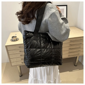 Rear view of a large black quilted tote bag with wide shoulder straps for daily commute
