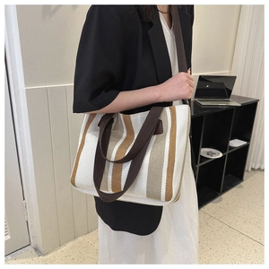 Detailed side view of a large striped canvas tote bag showing dual straps and texture