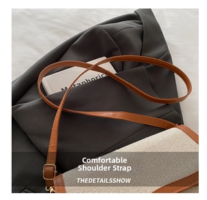 Detail of adjustable leather strap and metal buckle on canvas shoulder bag