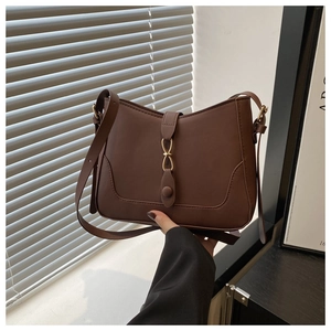 Dettaglio borsa in similpelle marrone con fibbia dorata e tracolla regolabile