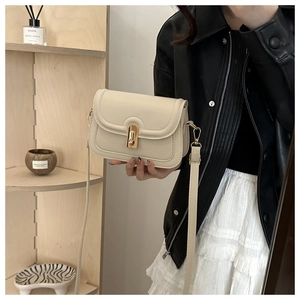 Detail of a creamy white leather mini crossbody bag with a golden turn-lock clasp