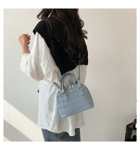 Detail of light blue quilted shell bag showing adjustable strap and golden zipper hardware