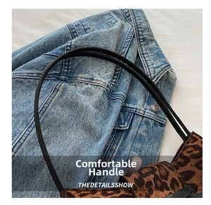 Close-up of leopard print bag featuring round black handles against denim fabric background