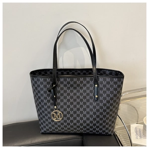 Close-up of a large-capacity black tote bag with gray M-pattern and gold logo charm
