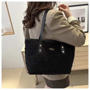 Detail view of black textured shearling tote bag with leather straps and gold rivets