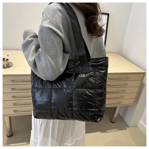 Lifestyle view of a large black quilted tote bag being worn for daily office commute