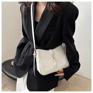 Detail of white PU leather crossbody bag with elegant gold infinity buckle and slim strap