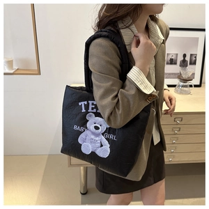Detail of black quilted tote bag featuring a purple bear print and thick padded handles