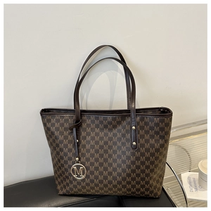Detailed macro of vintage brown tote bag featuring letter M monogram and gold metal tag