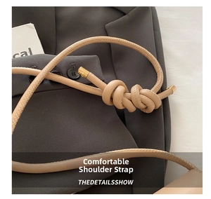 Detail of beige leather strap with decorative knot and cylindrical gold metal end caps