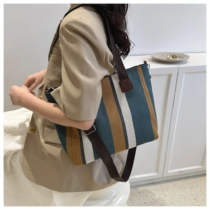 Vertical striped canvas tote bag with brown straps shown on a model's shoulder