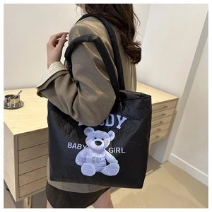 Detail of black quilted down tote bag with purple cartoon bear print and wide padded handles