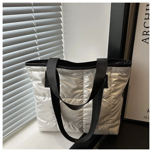 Detail of silver quilted tote bag showing padded texture and glossy metallic finish