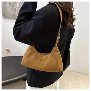 Detail of brown suede tote bag featuring adjustable strap metal buckle and zipper closure