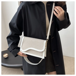 Detail of canvas crossbody bag featuring wave-shaped flap and white leather trim accents
