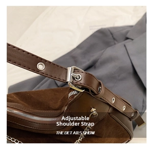 Details des verstellbaren Riemens mit silbernen Ösen und Kette an brauner Wildledertasche