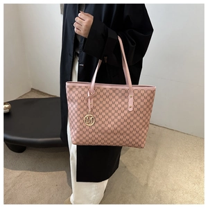 Close-up of pink monogram tote bag with gold M-shaped metal logo tag and fine texture