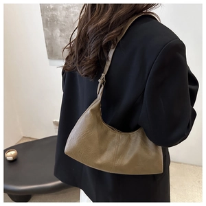 Sac hobo croissant en cuir marron vu de profil sur un mannequin en blazer noir