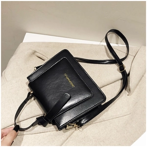 Détail de la texture cuir noir et logo doré sur ce sac à bandoulière minimaliste
