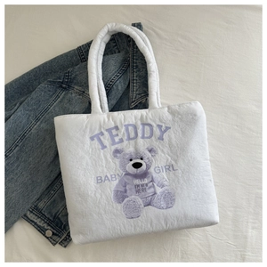 Close-up of white quilted canvas tote with purple teddy bear and soft padded handles