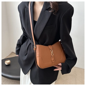 Borsa a tracolla in pelle marrone vintage indossata con blazer nero e gonna bianca