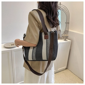 Detail of vintage striped canvas tote bag showing thick brown shoulder strap and D-ring