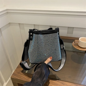 Stylish rhinestone bucket bag with black and white wide strap shown in a modern setting
